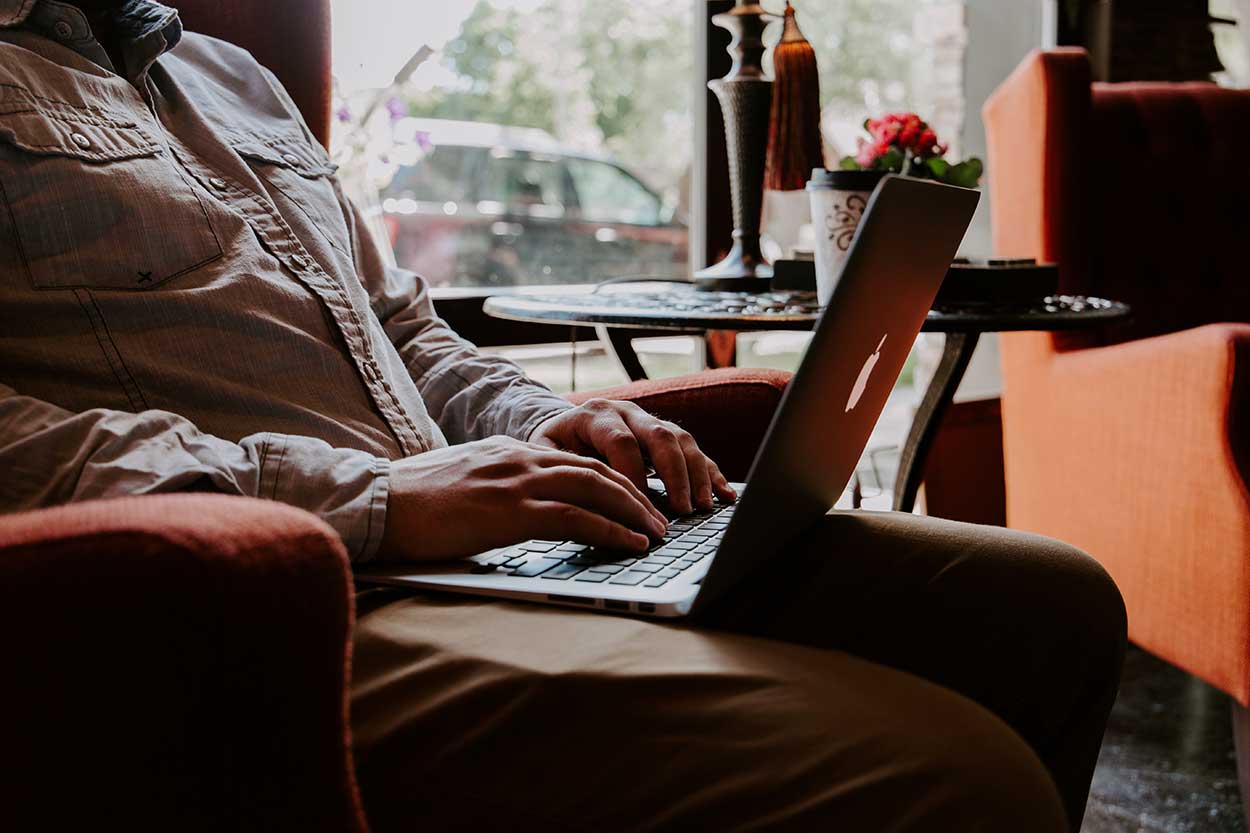 man using apple laptop to research car insurance premiums on used cars