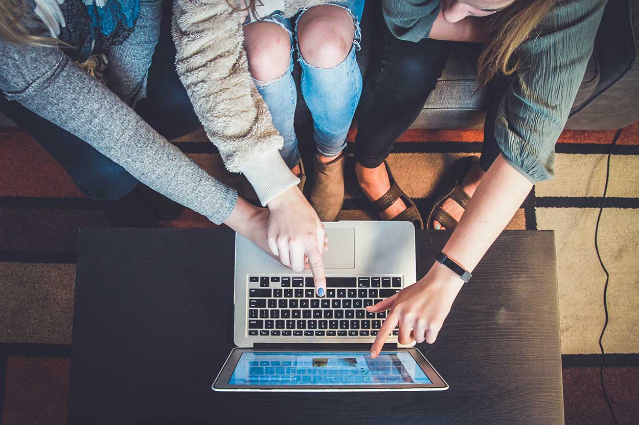 students gather around laptop to research how to improve your credit score