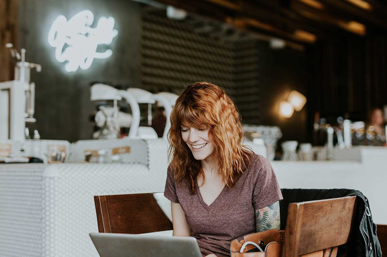 Red headed lady on laptop looking for the best way to finance a car