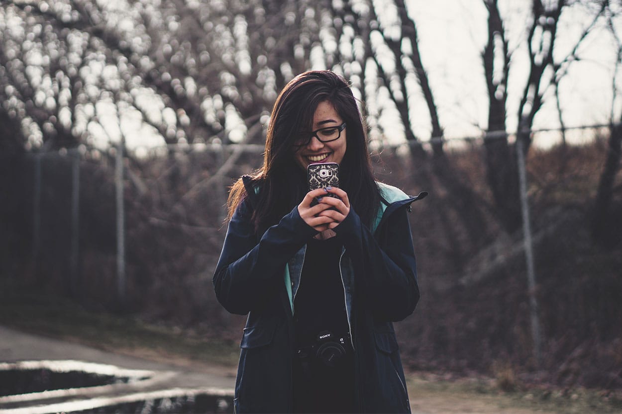 Young lady looking happily at her phone due to getting car finance with poor credit