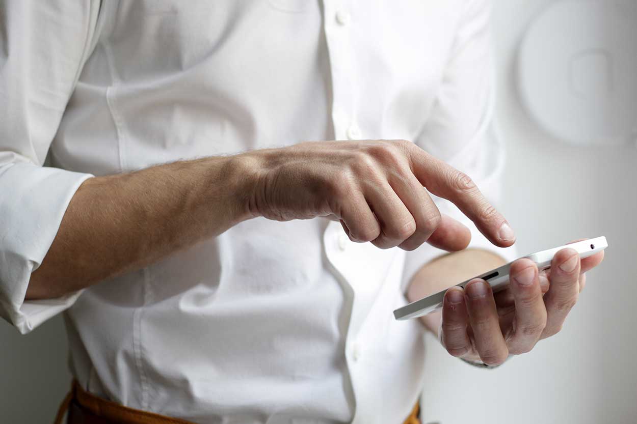 Man with sleeves rolled up using his phone to check if he can get a payment holiday