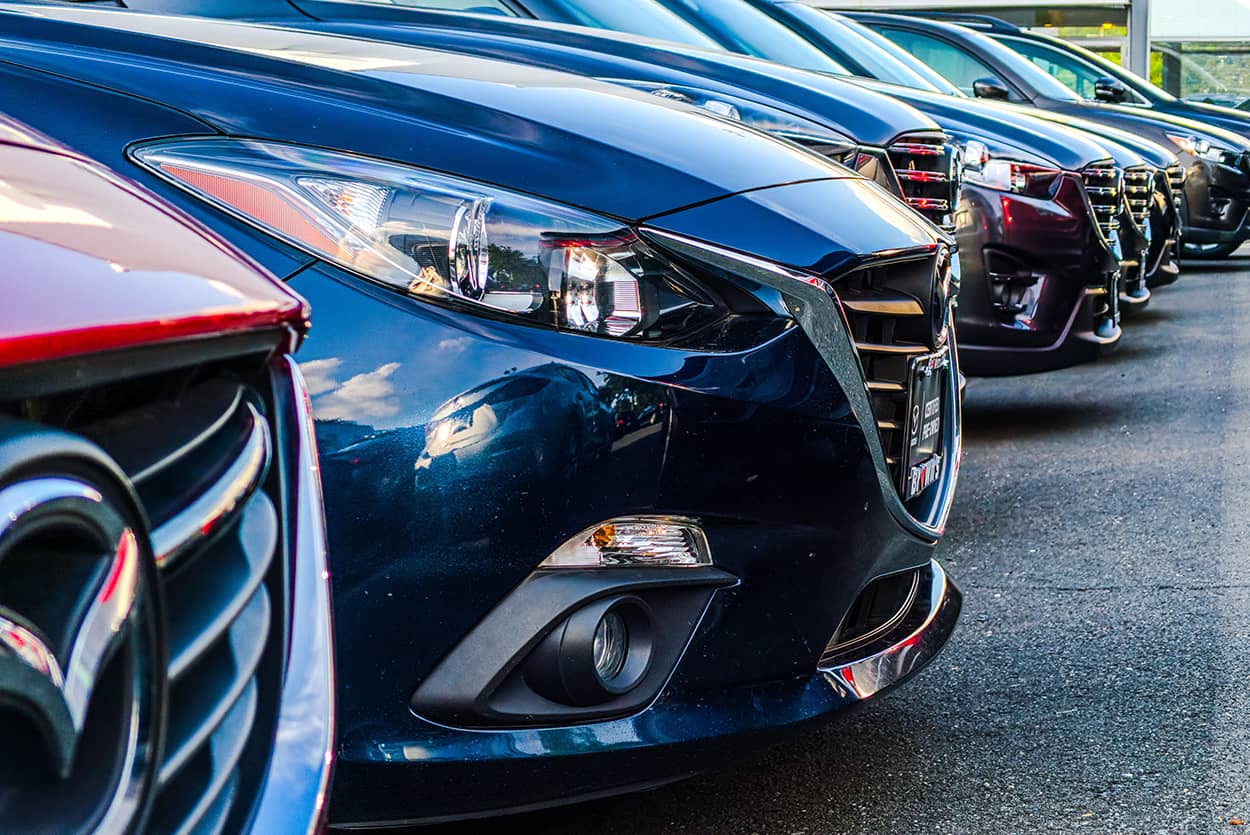 Row of new and used cars outside a car dealership