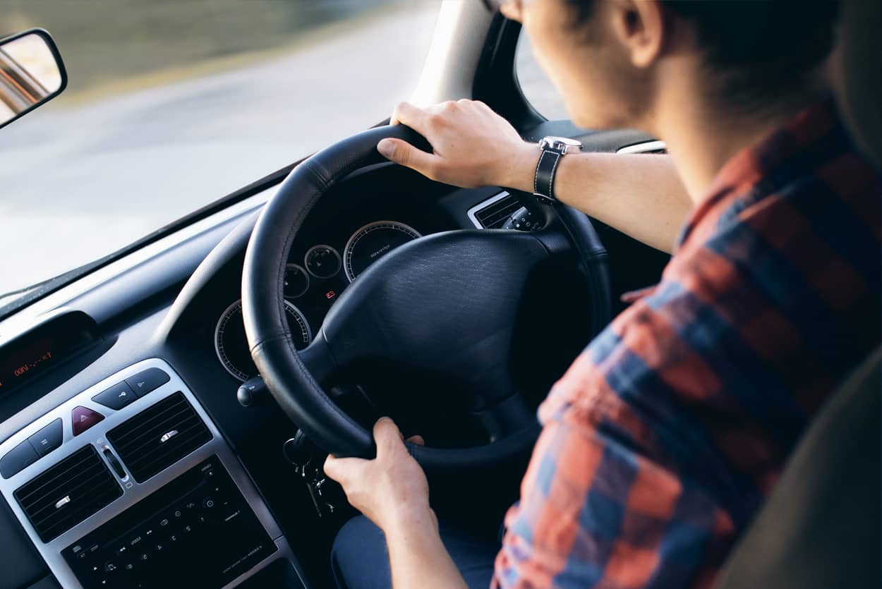 Man driving his car with new lower car insurance cost