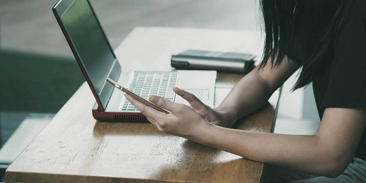 Woman with laptop using her phone