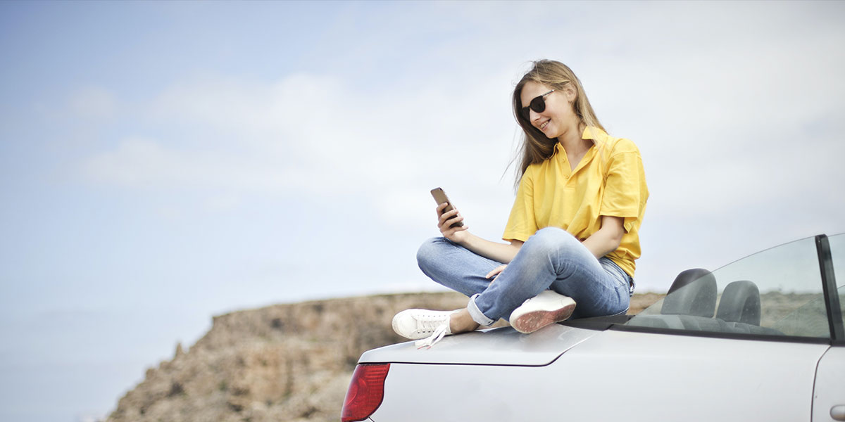 Woman sat on car checking her credit score