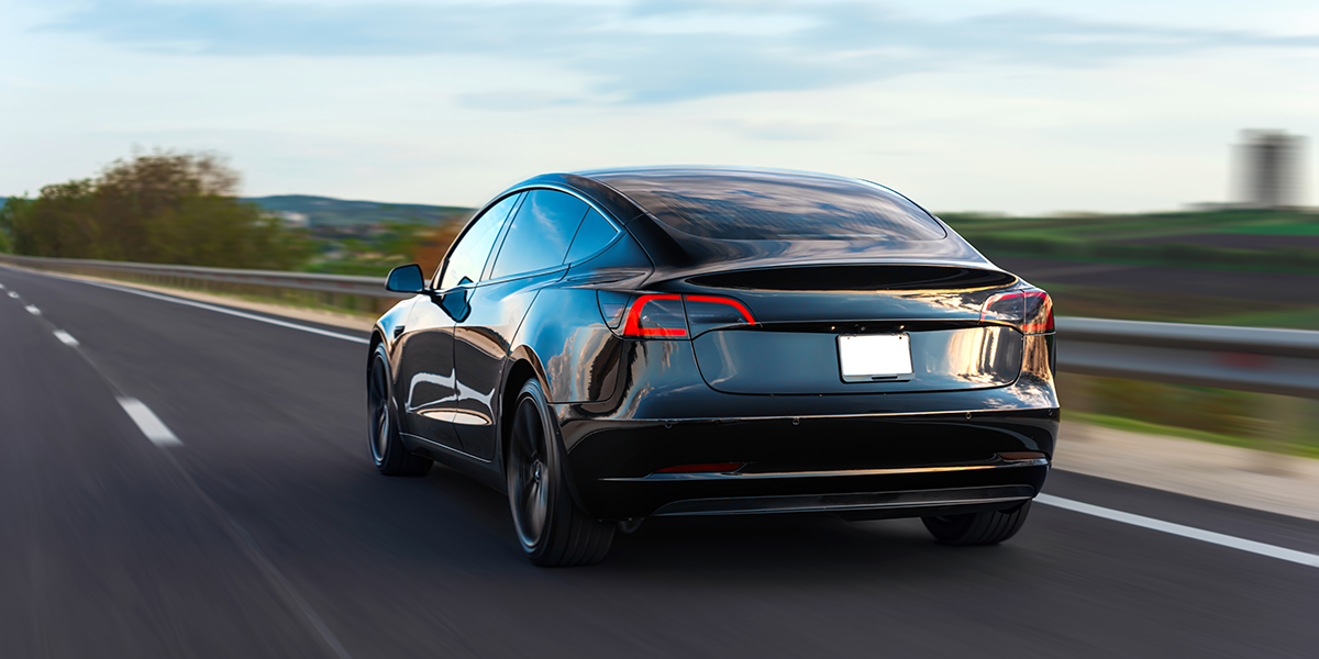 Black Tesla driving down the road bought with a Balloon Payment