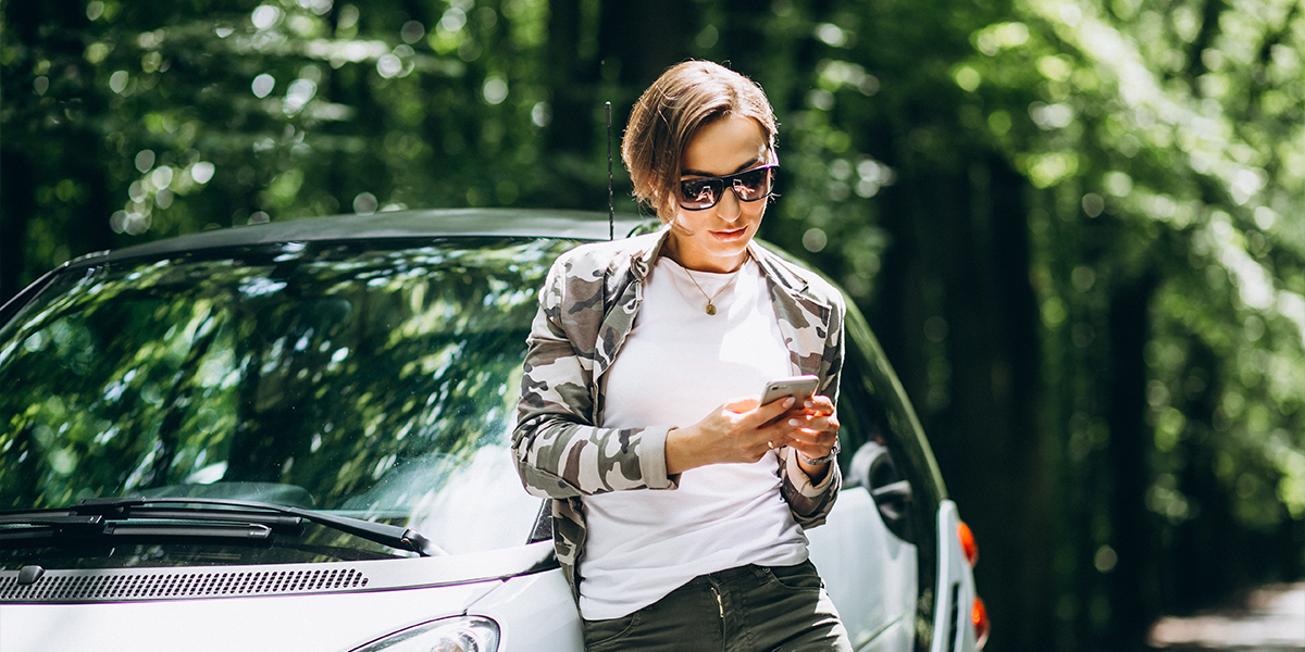 Woman stood by her car refinancing her balloon payment on a mobile phone