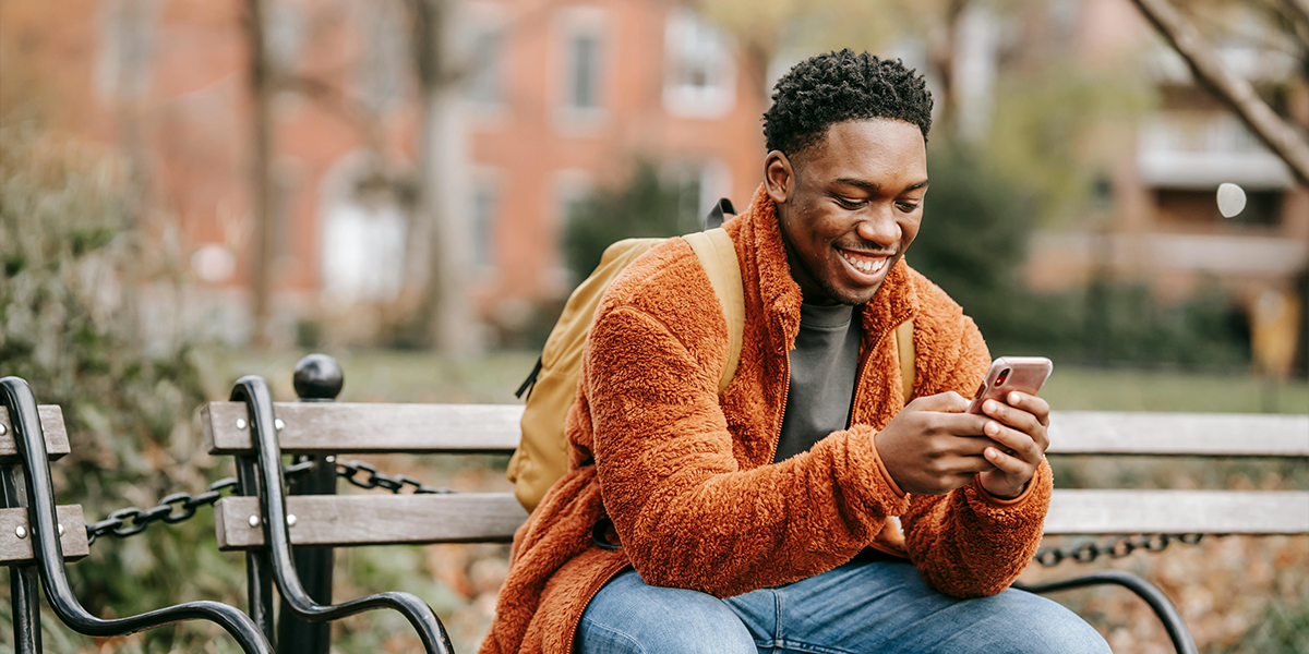 Man checking his phone sat on a bench