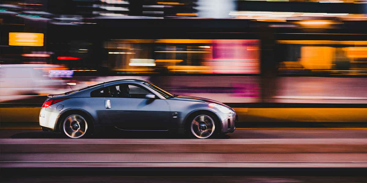 Silver car driving through a city at night