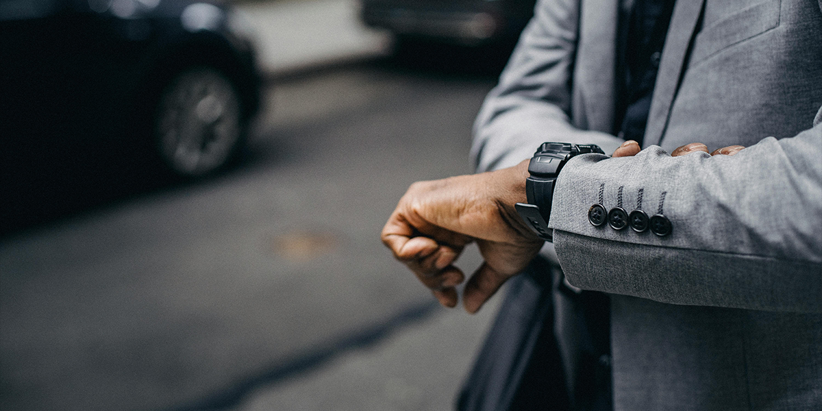 Man in grey suit looking at his watch to check the time