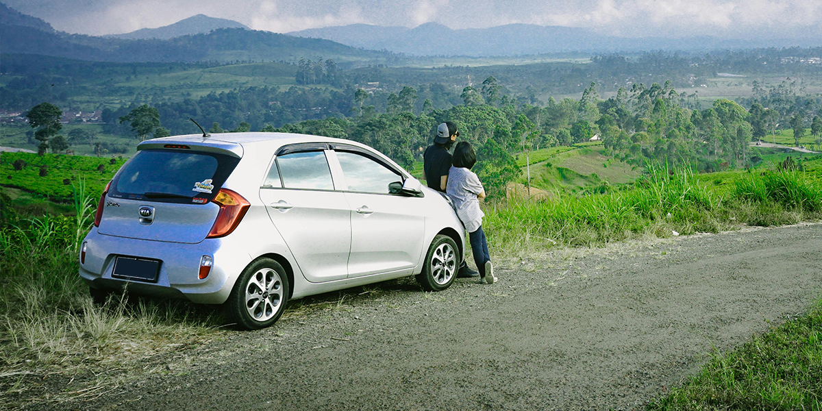 Couple stood next to a silver car bought using a car loan