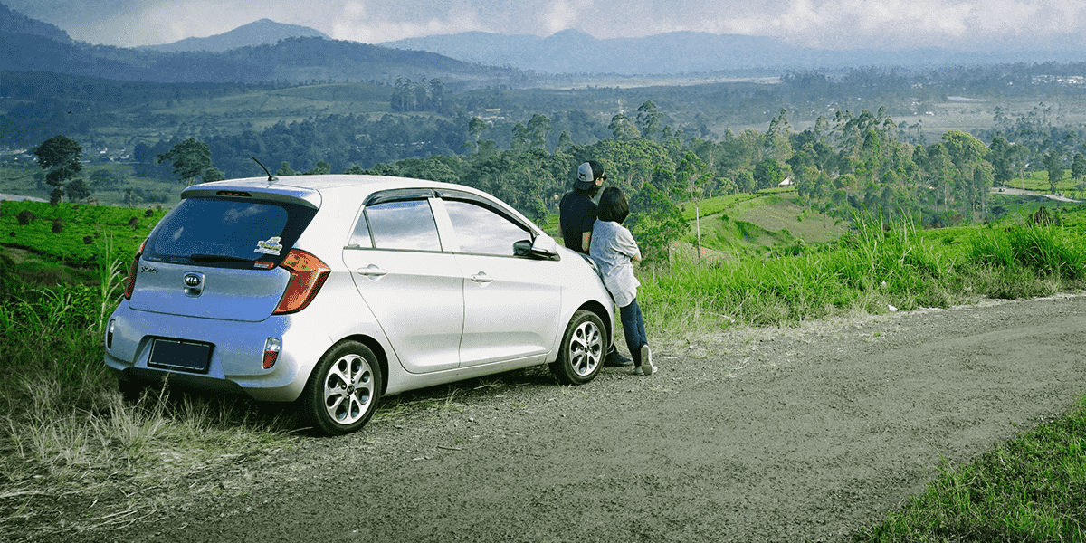 Couple stood next to a silver car bought using a car loan