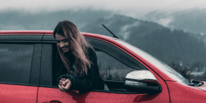 Woman leaning out of a red car purchased on PCP